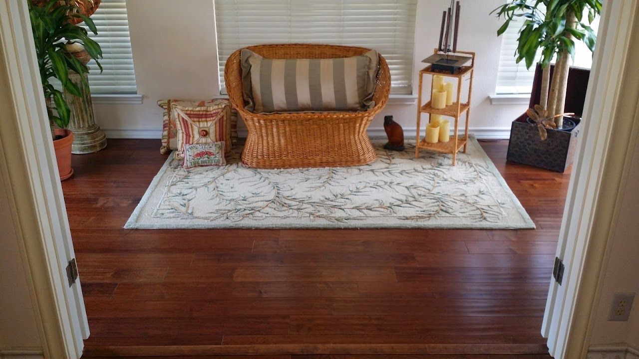 A living room with a wicker couch and a rug on the floor