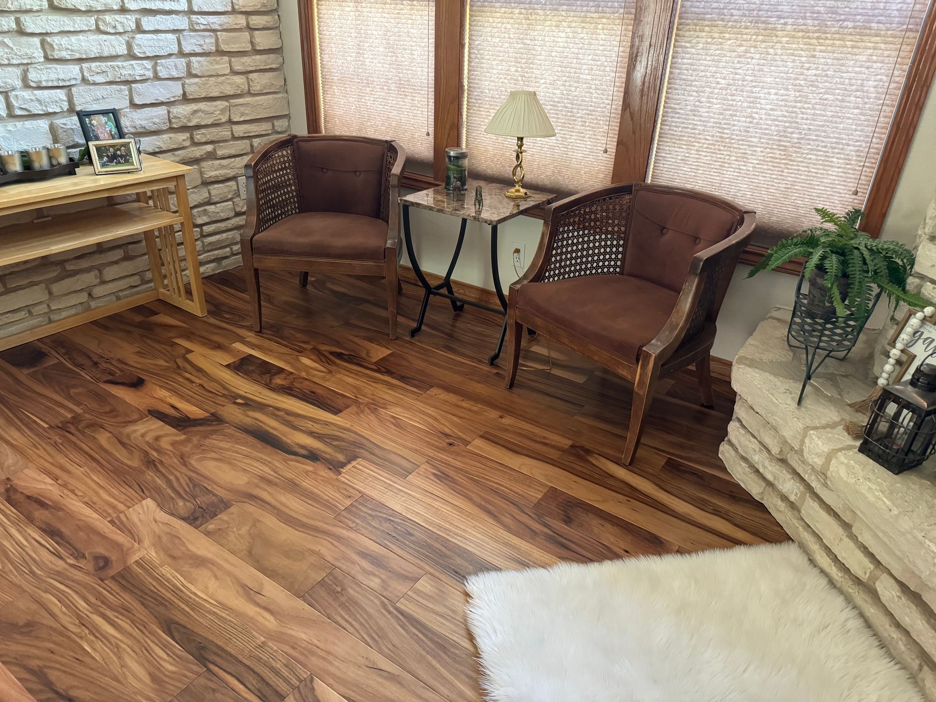 A living room with hardwood floors, two chairs, a table, and a fireplace.