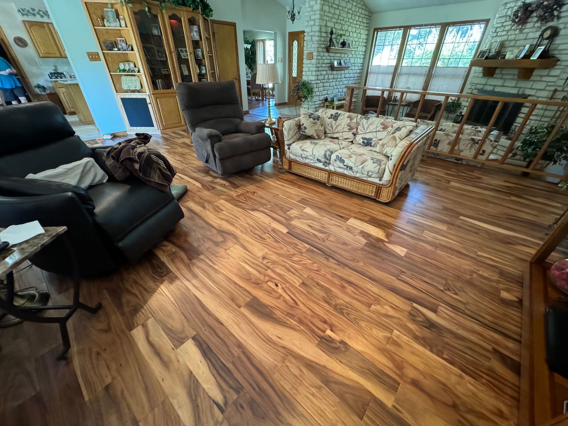 A living room with hardwood floors, a couch, chairs, and a fireplace.