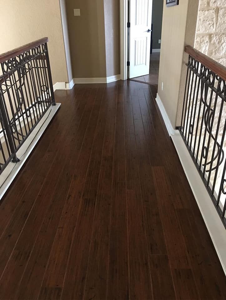 A hallway with hardwood floors and a wrought iron railing.