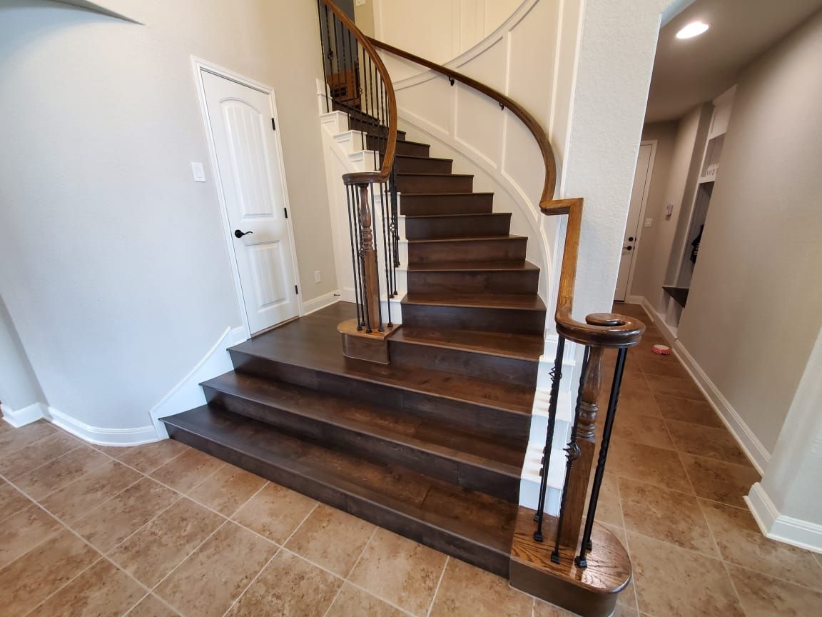 A wooden staircase with a curved railing in a hallway.