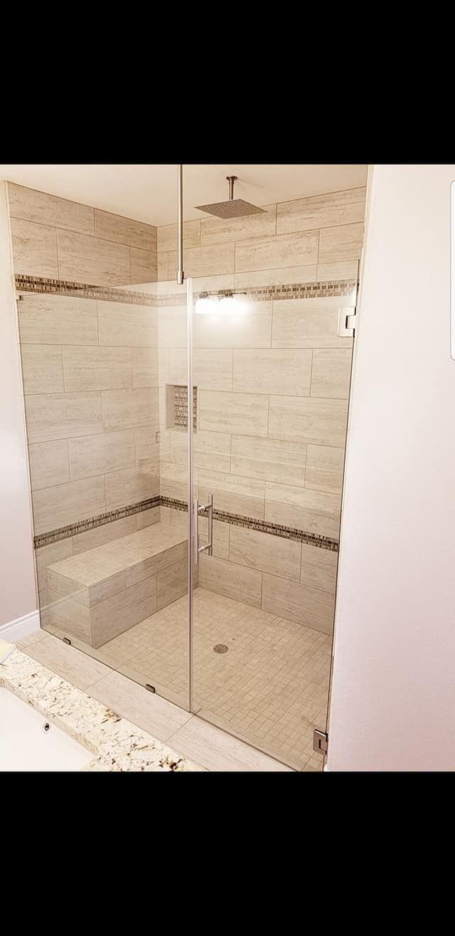 A bathroom with a walk in shower and a bench.