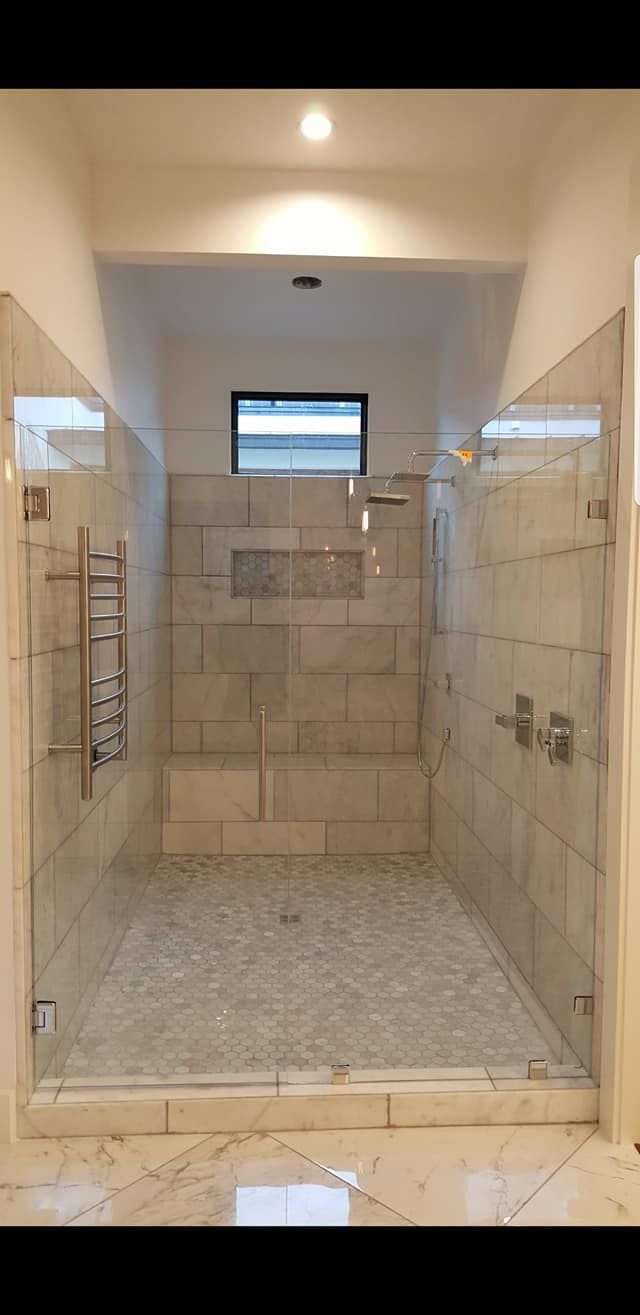 A large walk in shower with a glass door and a window.
