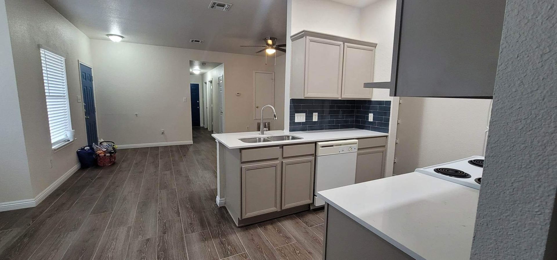 A kitchen with a stove , sink , and dishwasher in an empty house.