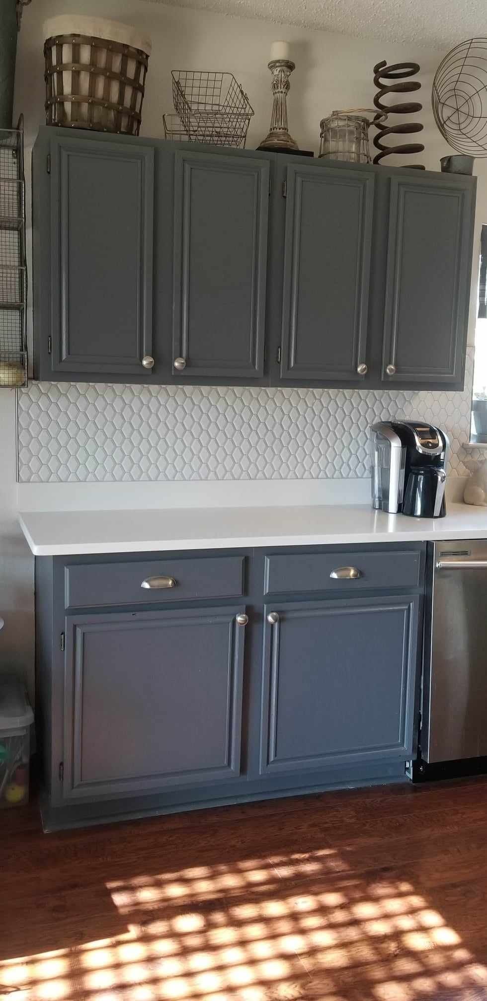 A kitchen with gray cabinets and a stainless steel dishwasher.
