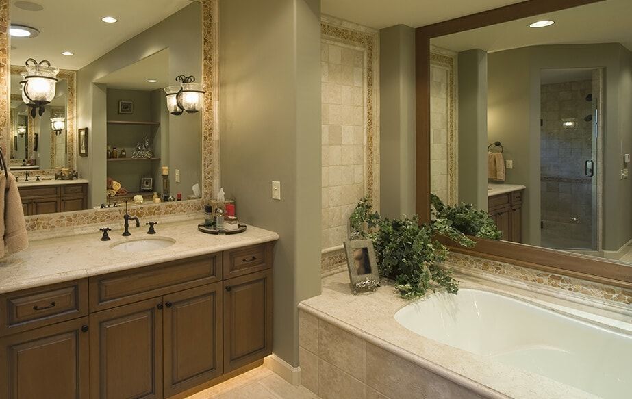 A bathroom with two sinks , a tub and a large mirror.
