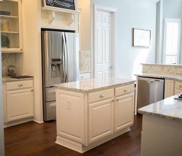 A kitchen with white cabinets and a large island in the middle