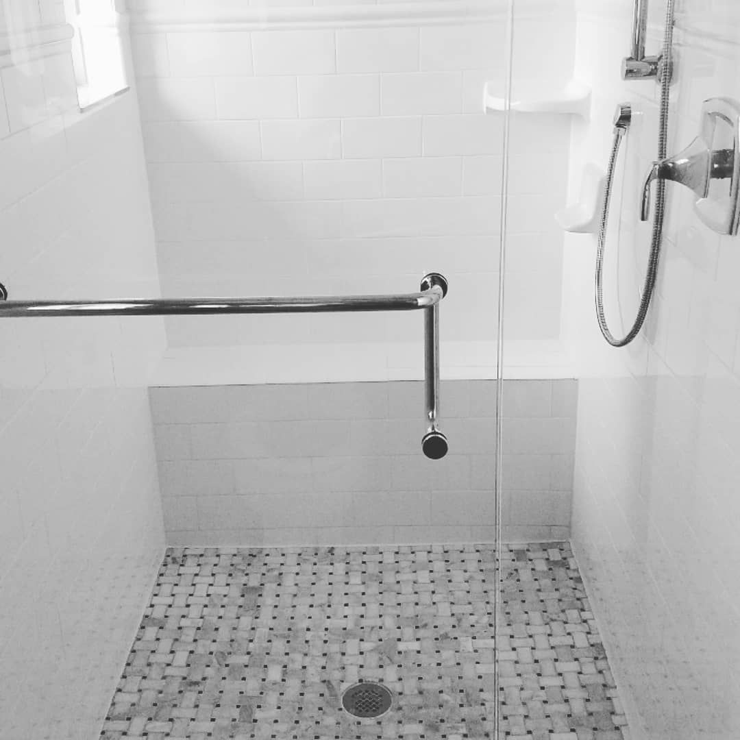A black and white photo of a walk in shower with a glass door.