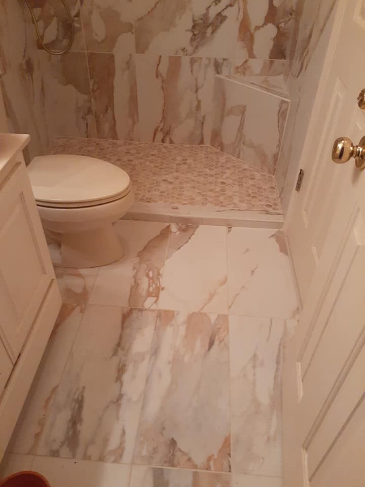 A bathroom with a toilet , sink , and marble floor.