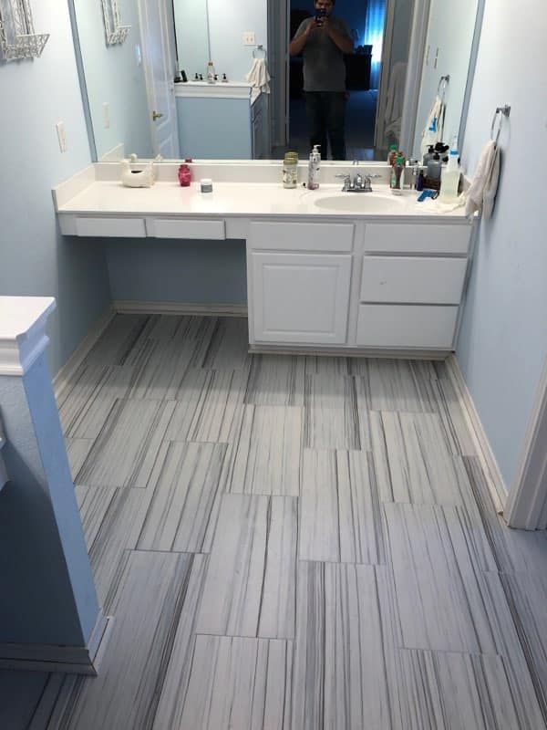 A bathroom with two sinks , a mirror and a tiled floor.