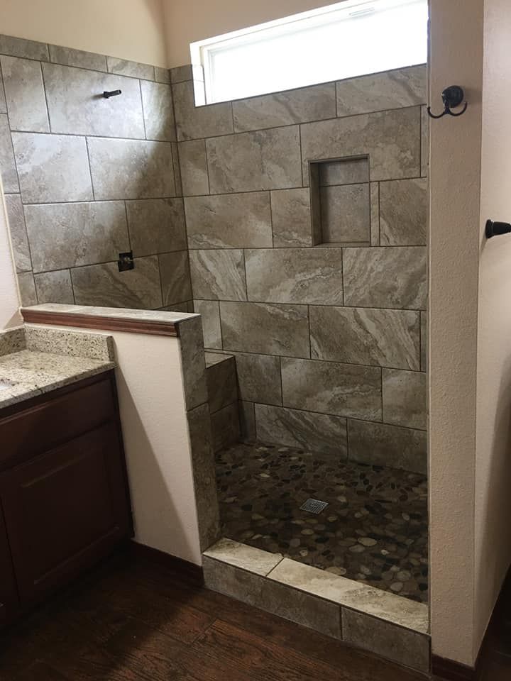 A bathroom with a walk in shower and a sink.