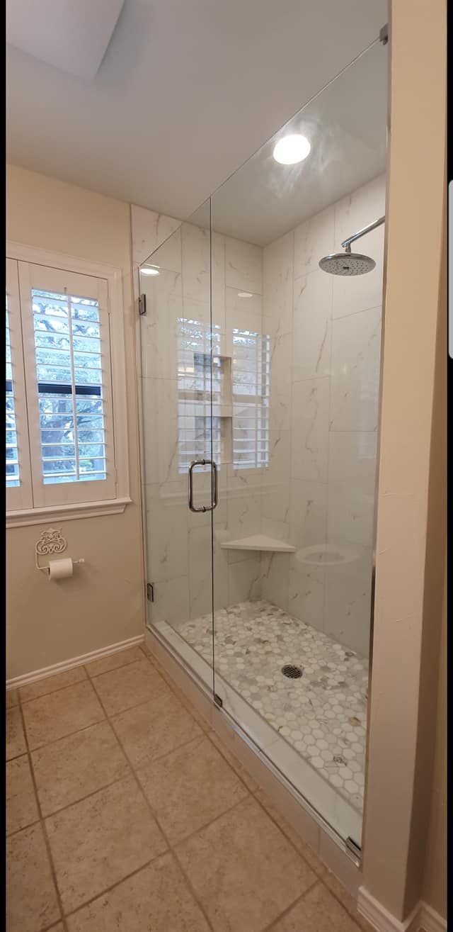 A bathroom with a walk in shower and a window.