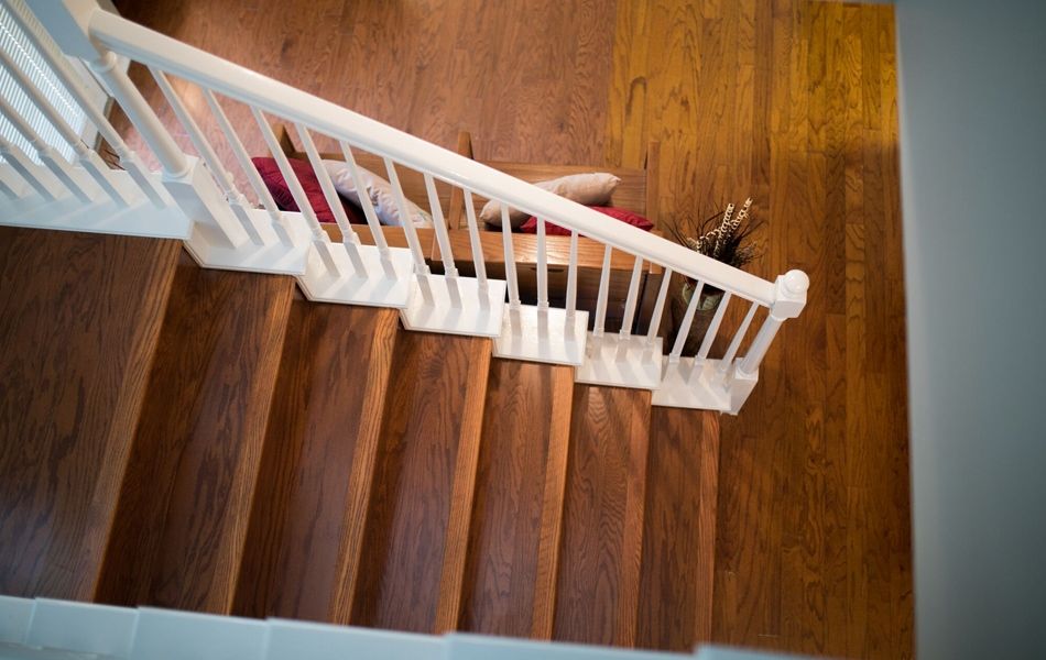 An aerial view of a wooden staircase with a white railing.