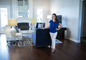 A woman is standing in a living room in a new home.