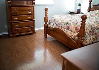 A bedroom with a bed, dresser, nightstand, and lamp.