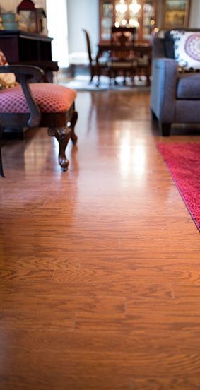 A living room with hardwood floors and a dining room in the background.