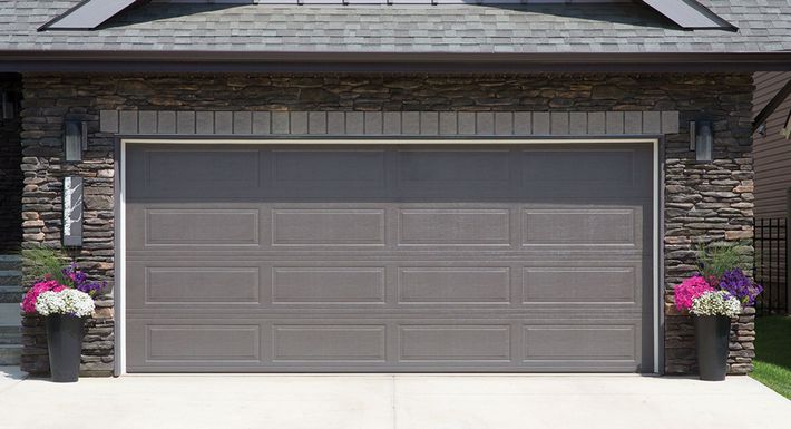 A garage door with flowers in pots in front of it.