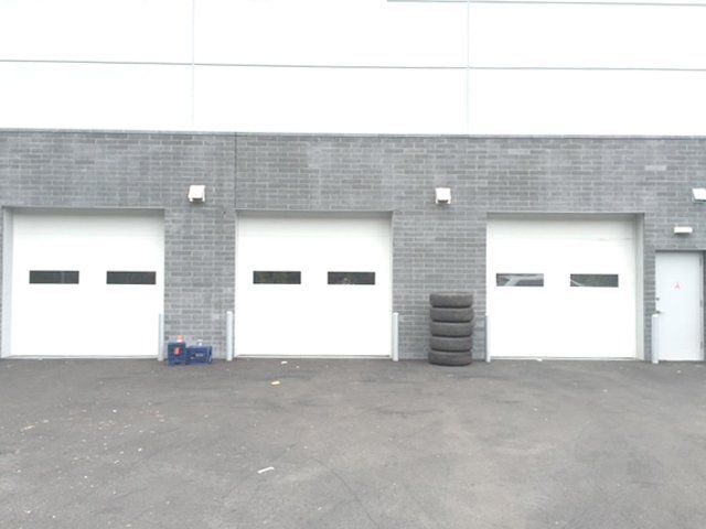 A row of white garage doors on a brick building