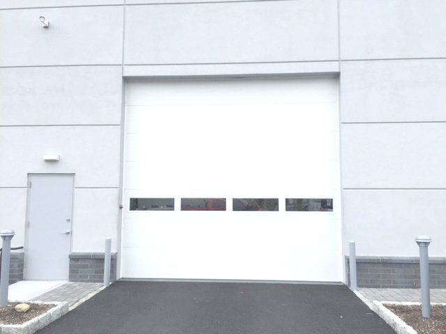 A white garage door with a black driveway leading to it