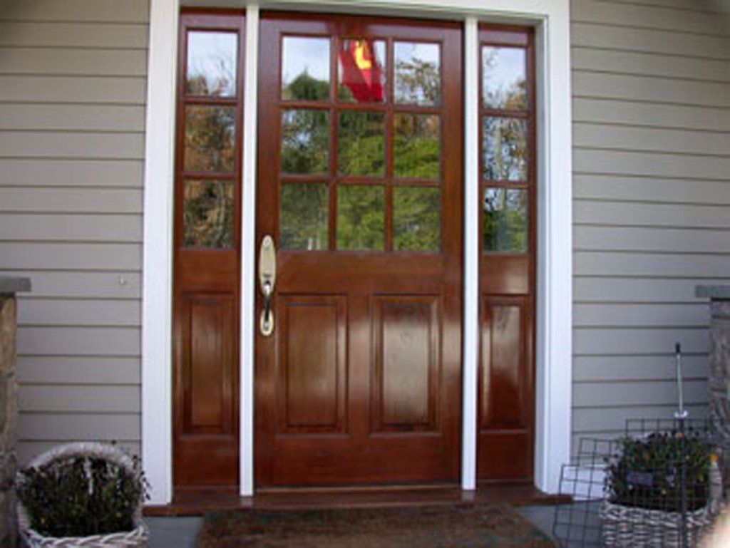 A large wooden door with a lot of windows is on the front of a house.