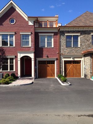Two brick houses with wooden garage doors are next to each other