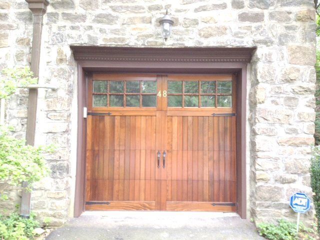 A wooden garage door is in front of a stone building.