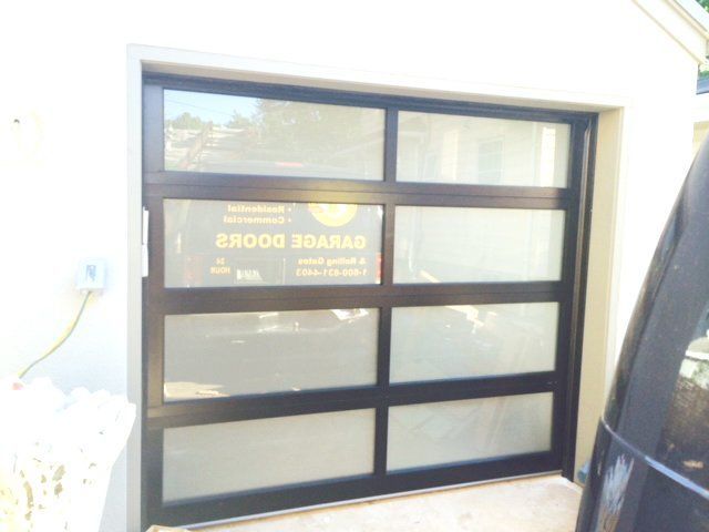 A black car is parked in front of a garage door