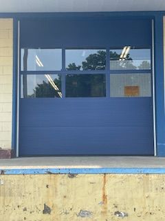 A blue garage door with a lot of windows is sitting on a dock.