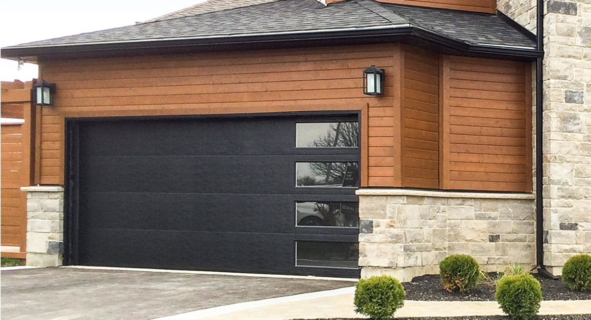A black garage door is on the side of a house.