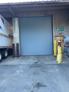 A truck is parked in front of a large blue garage door.