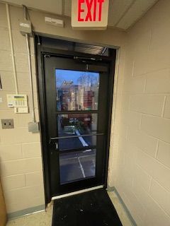 A black door with a red exit sign above it.