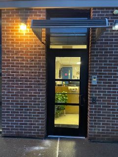 A brick building with a black door and a canopy over it.