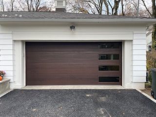 A white house with a brown garage door and a driveway.