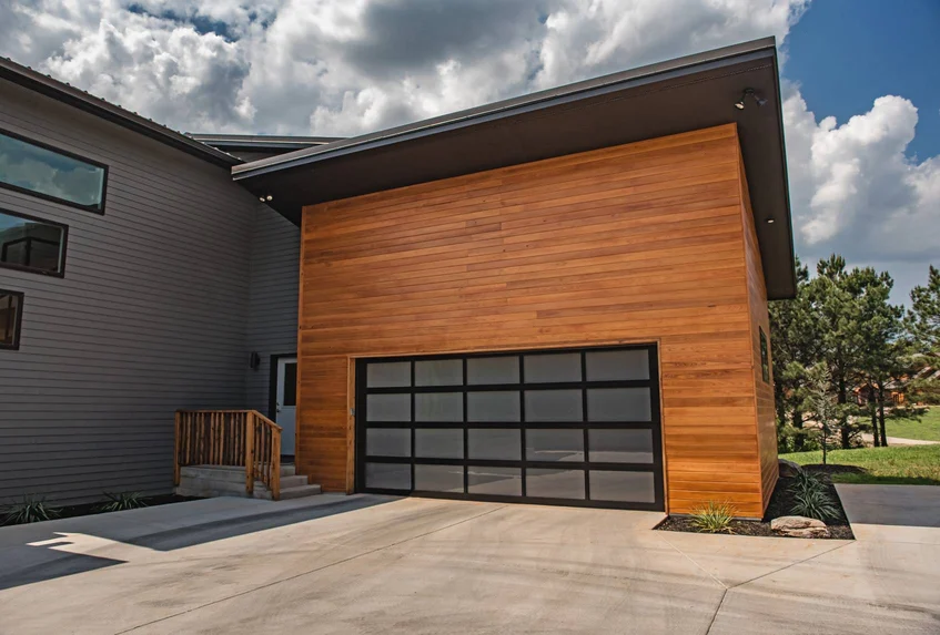 A modern house with a wooden garage door and a concrete driveway.