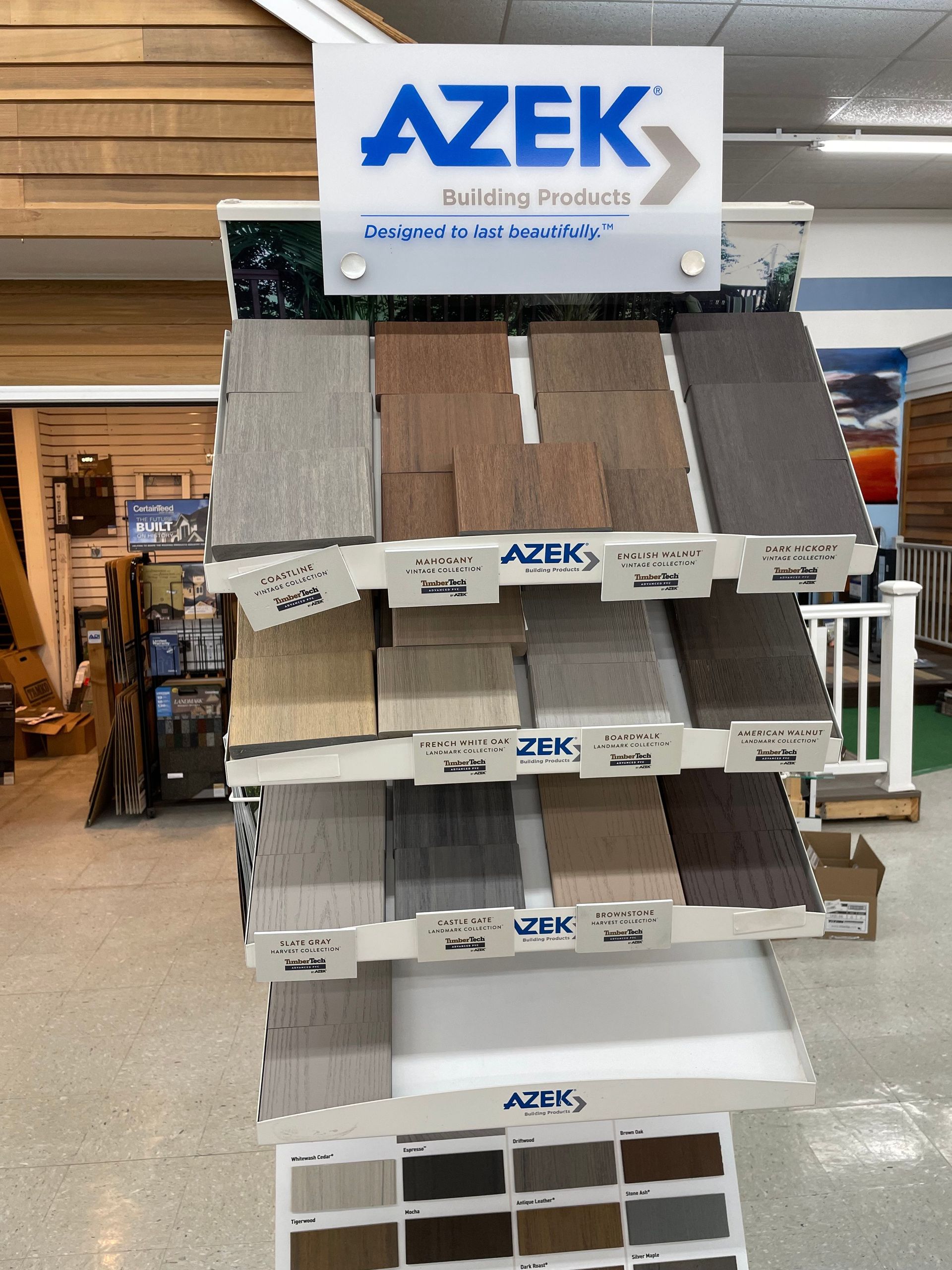 Display of AZEK decking samples in various colors. Showroom setting with other building materials.