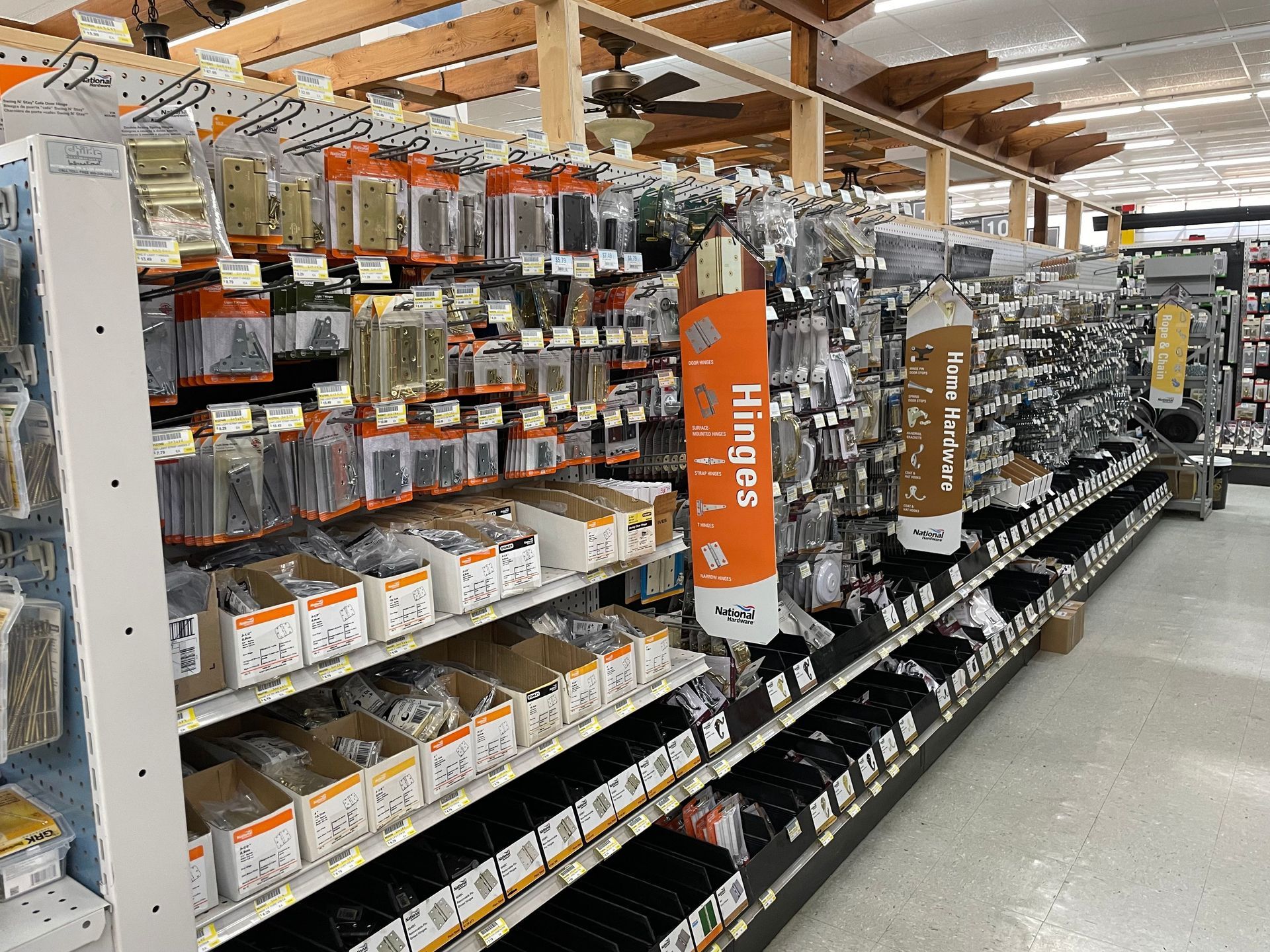 Hardware store aisle stocked with various hinges and hardware in packaging.