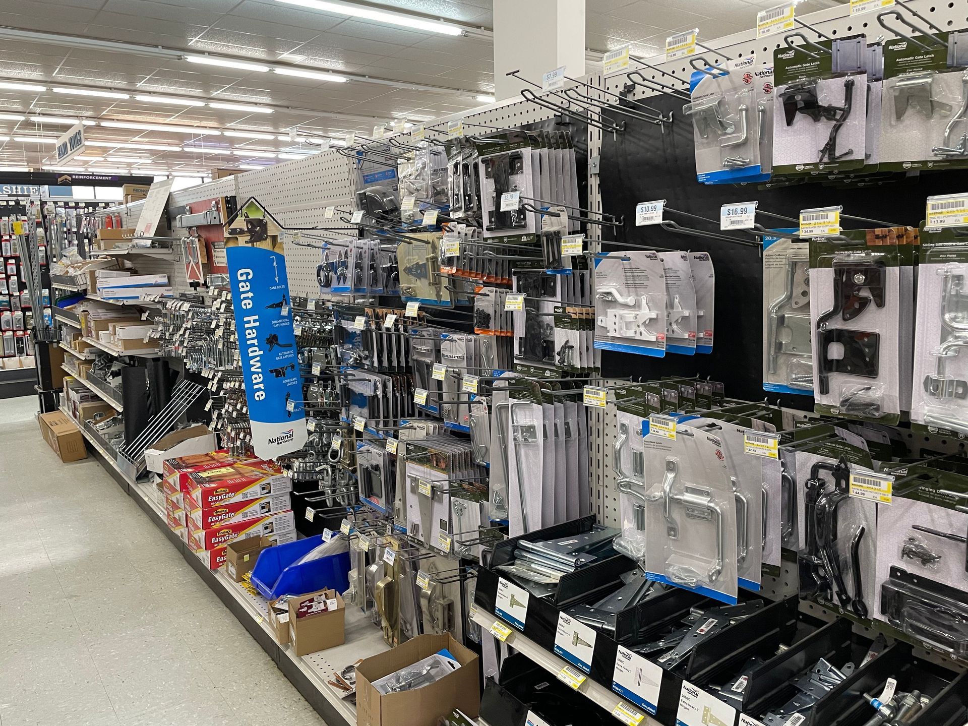 Hardware store aisle, various hardware and tools displayed on shelves and pegboards.