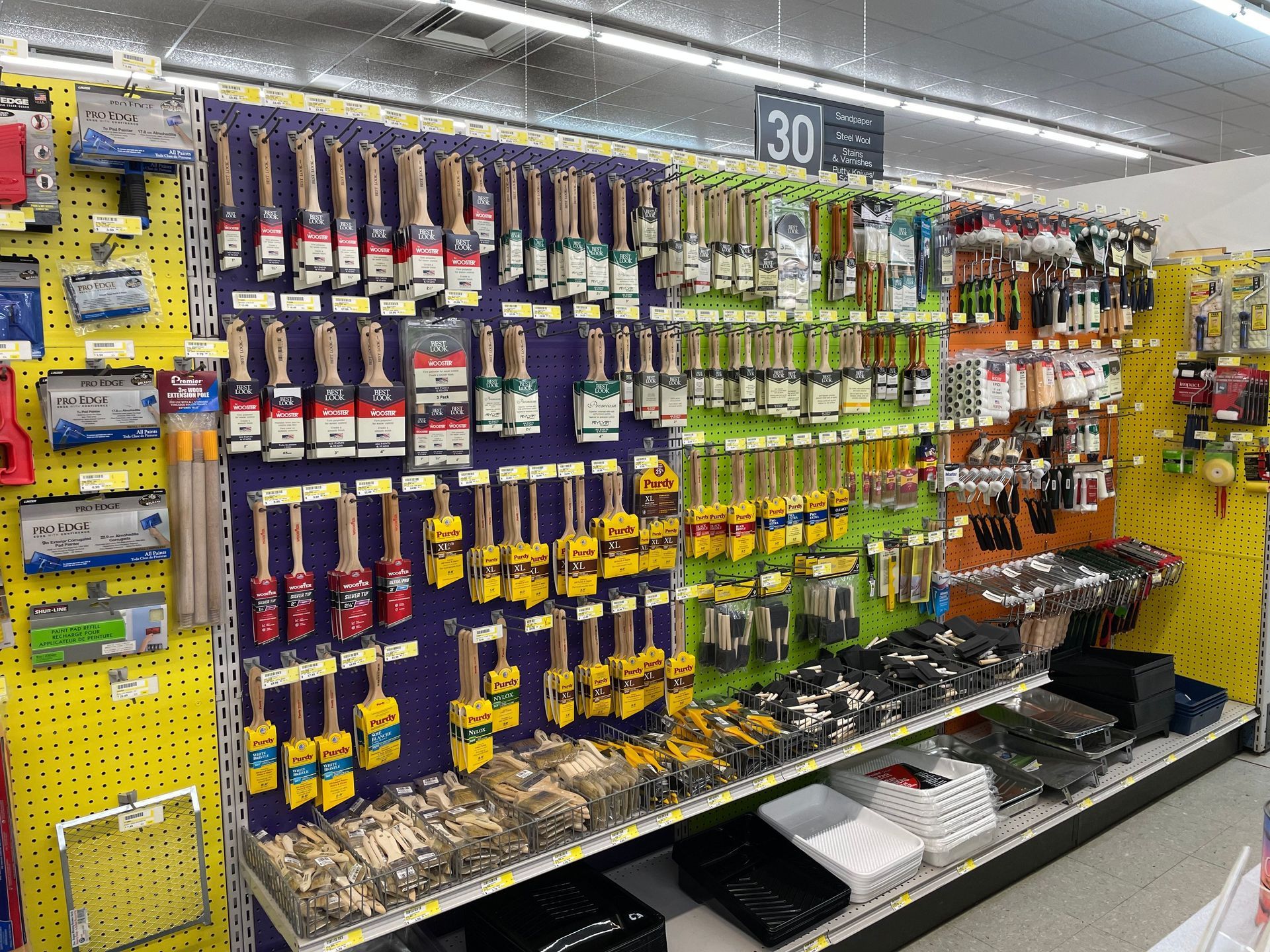 Paint brushes and supplies displayed on a store wall. Various brush sizes and colors.