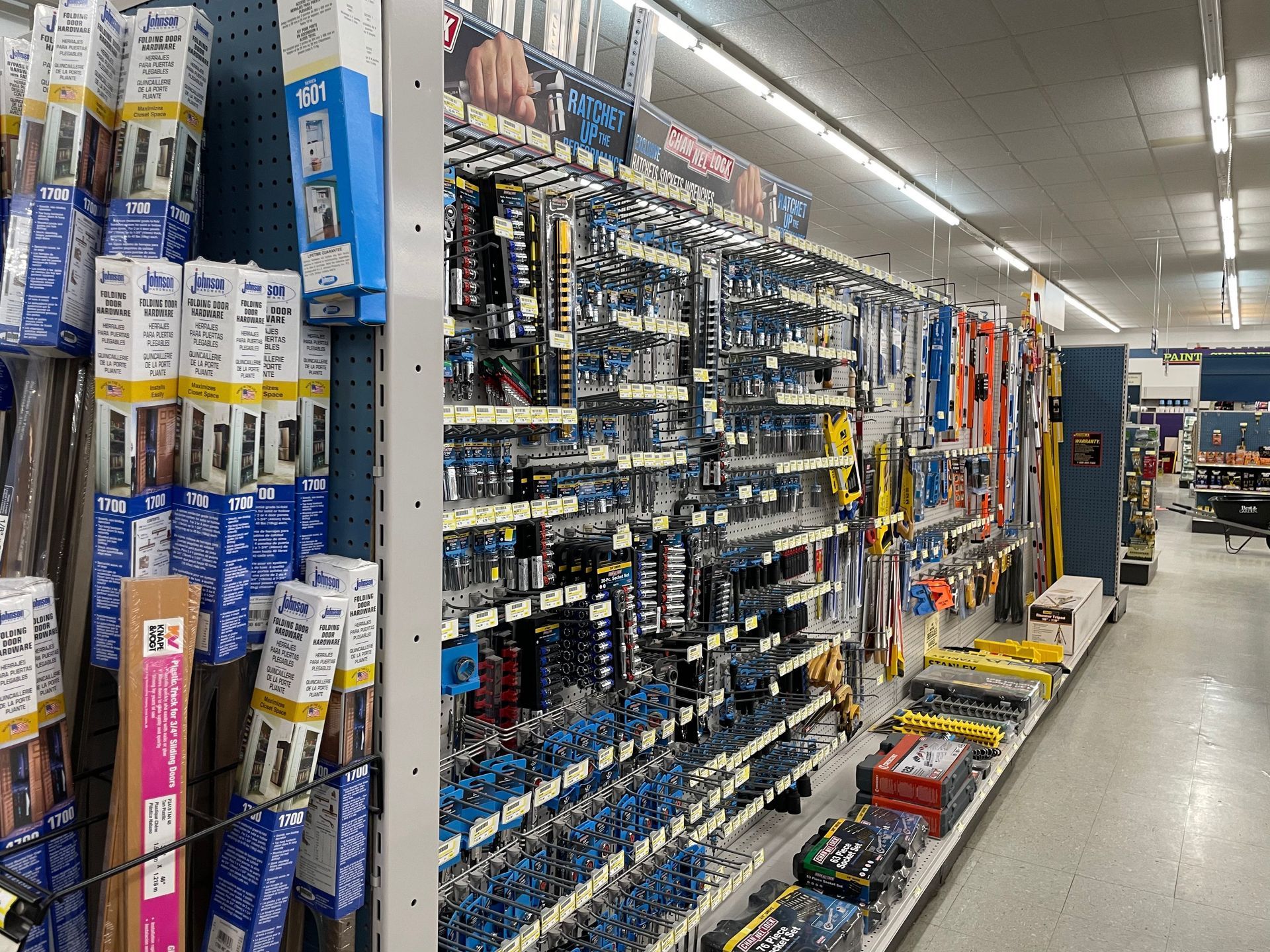 Tools and hardware displayed on shelves in a well-lit store aisle.