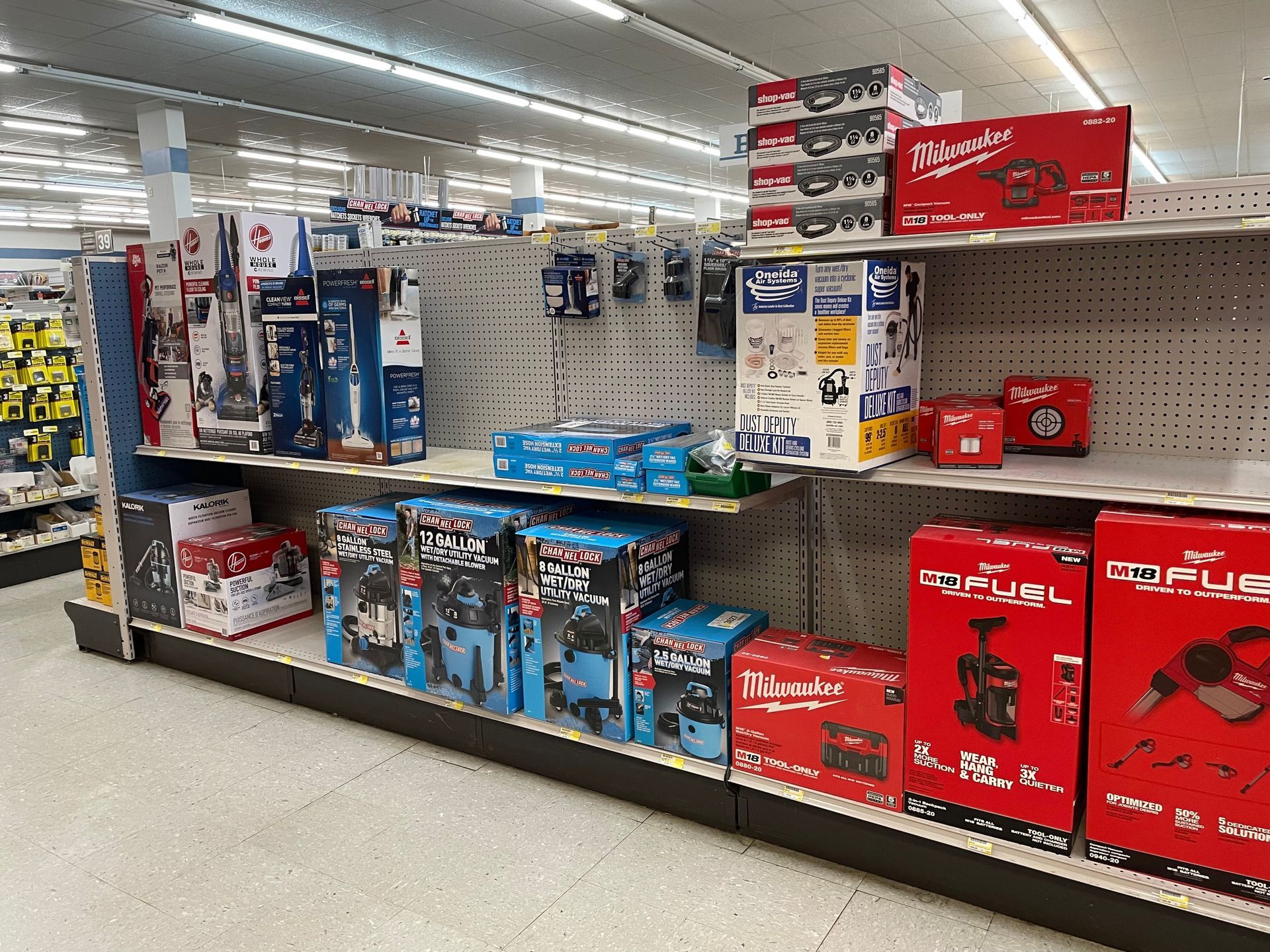 Shelves of power tools in a store. Milwaukee and other brand boxes are visible, with blue and red colors.