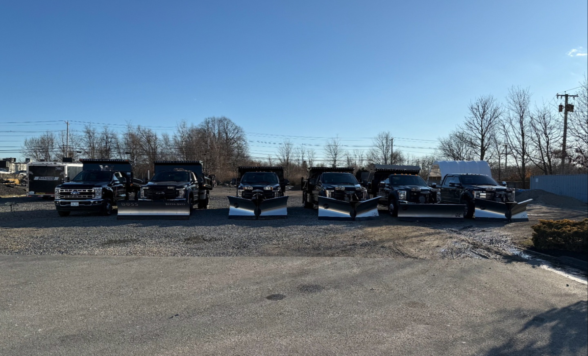 A yellow snow plow is parked in a parking lot