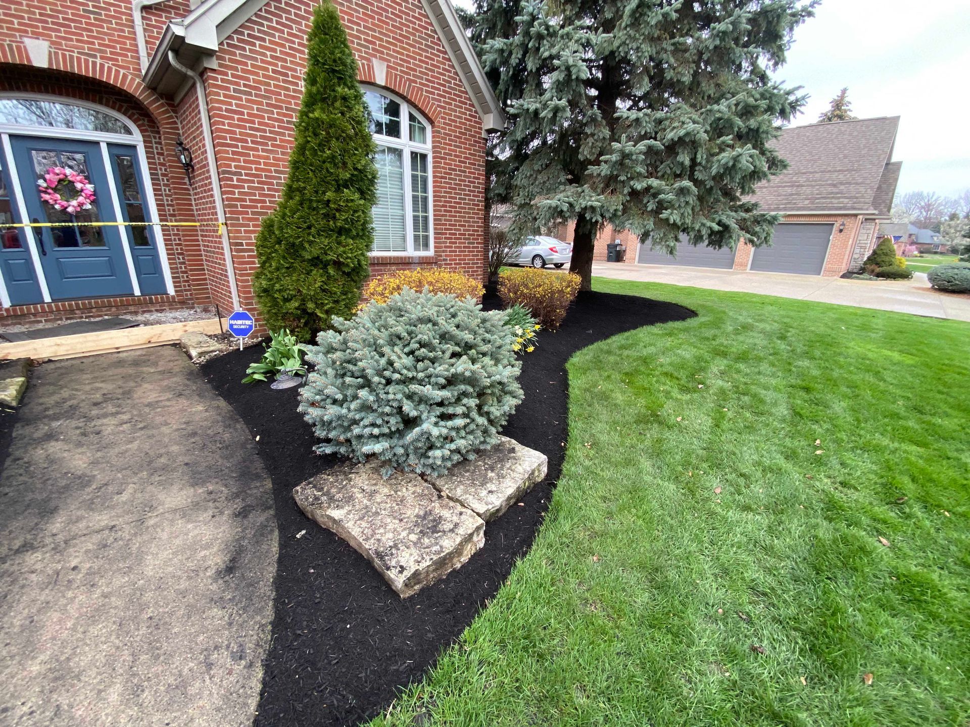 Brick house with manicured lawn and garden bed edged with black mulch.