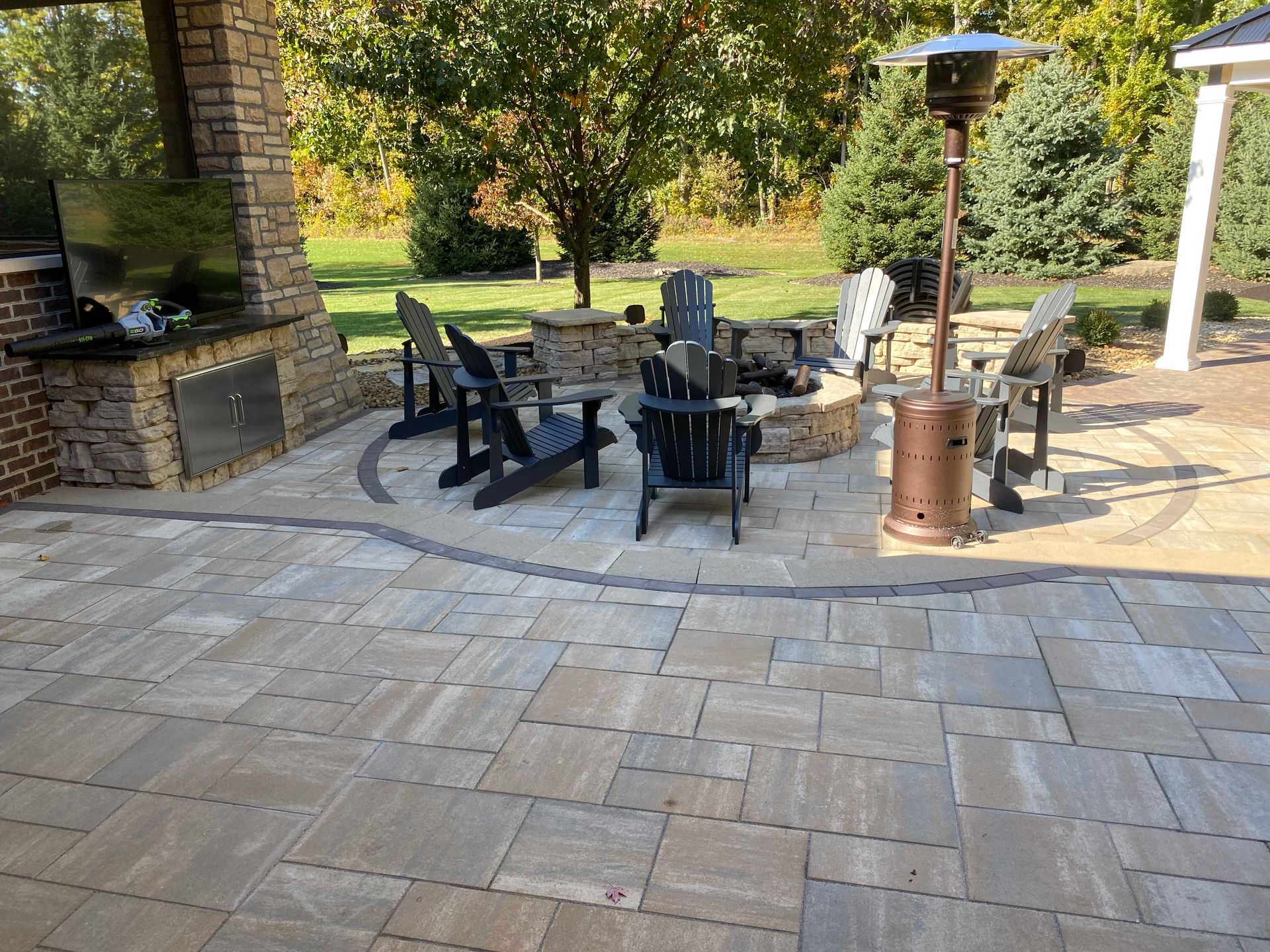 Outdoor patio with stone pavers, seating, fireplace, and heater.
