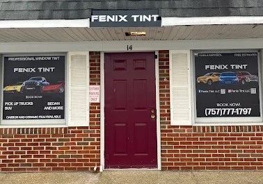 A brick building with a red door and a sign that says fenix tint.