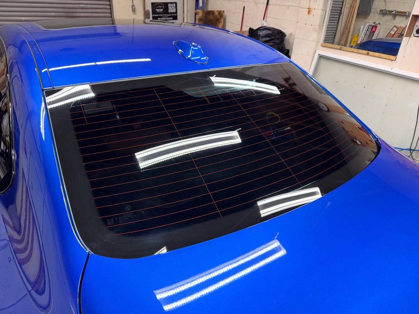 A blue car with a black windshield is parked in a garage.