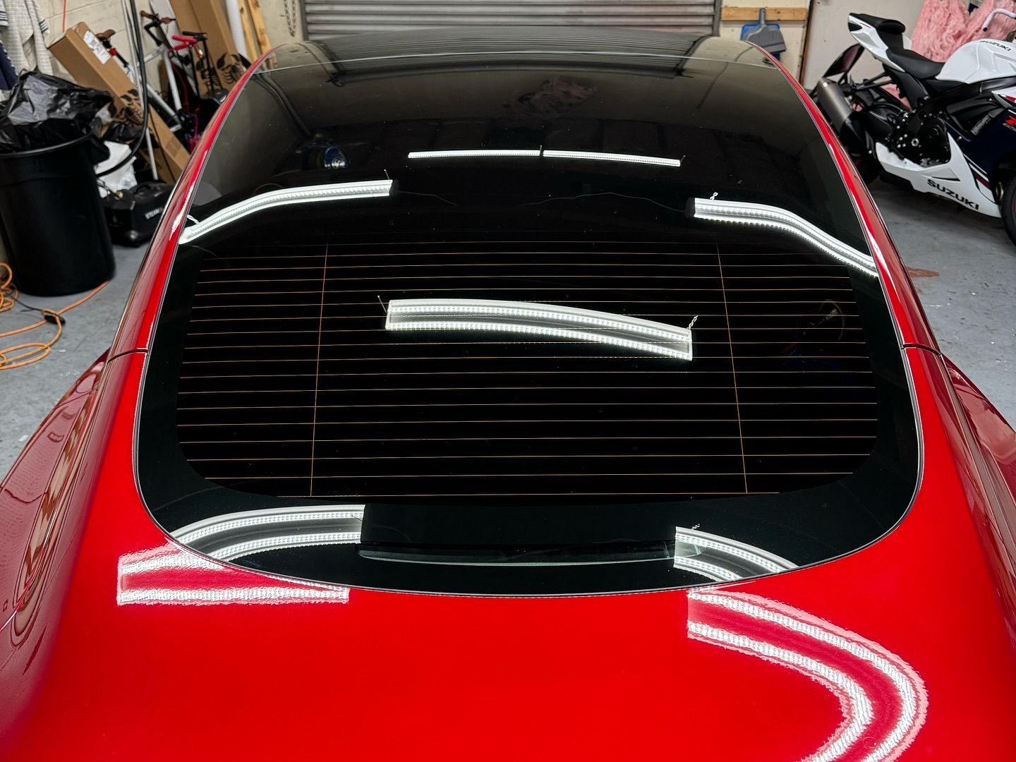 A red car with a black roof is parked in a garage.