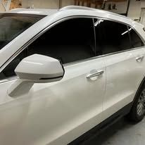 A white car with black windows is parked in a garage.