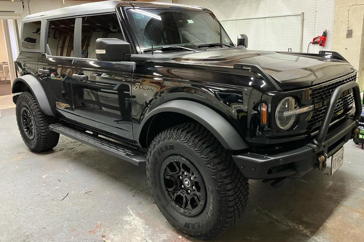 A black ford bronco is parked in a garage.