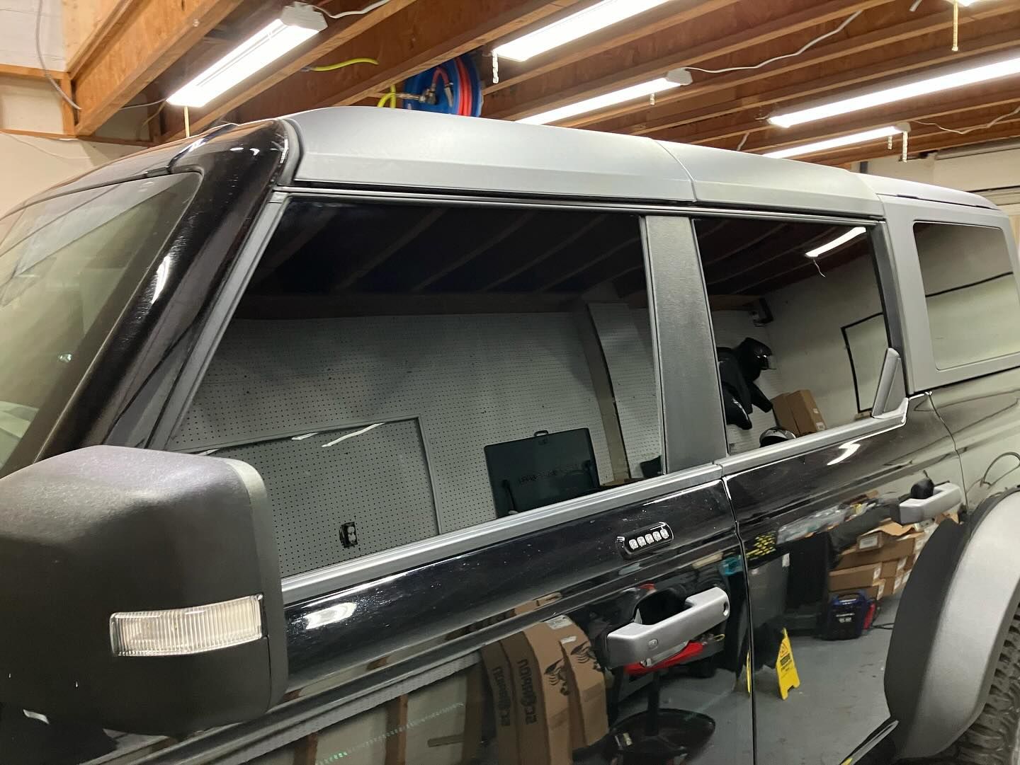 A jeep is parked in a garage with its doors open.