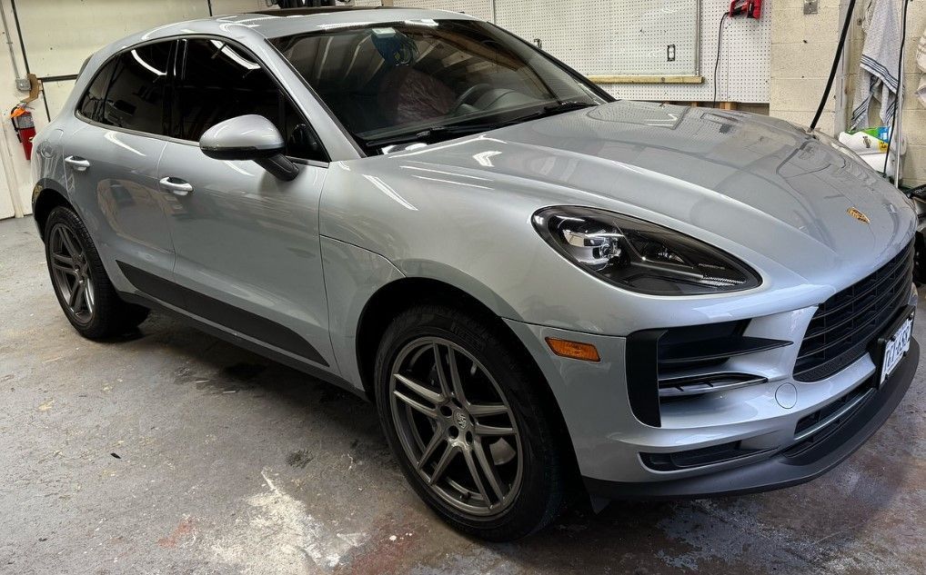 A silver porsche macan is parked in a garage.